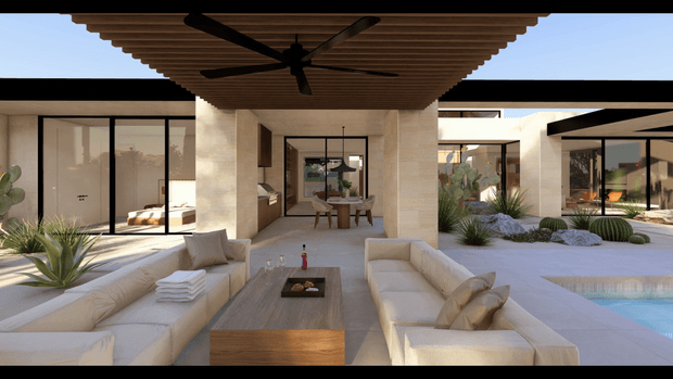A refined outdoor living space centered on a covered lounge terrace, with a timber slatted ceiling and large black ceiling fan overhead. Built-in cream upholstered seating surrounds a low timber coffee table and a dark inset fire feature. Pale stone or concrete paving, architectural columns, extensive glass walls, desert-style planting, and a swimming pool create a warm, resort-like courtyard setting. The open-plan interior and additional covered outdoor area are visible beyond.