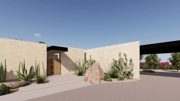 A minimalist single-storey desert-style building exterior with pale rendered or stone-clad walls, a dark projecting roof or canopy, a timber entry door, and a broad paved forecourt. Sculptural boulders and drought-tolerant planting including cacti, agaves, yuccas and succulents form the landscaped frontage, with a covered opening and flowering garden visible beyond.